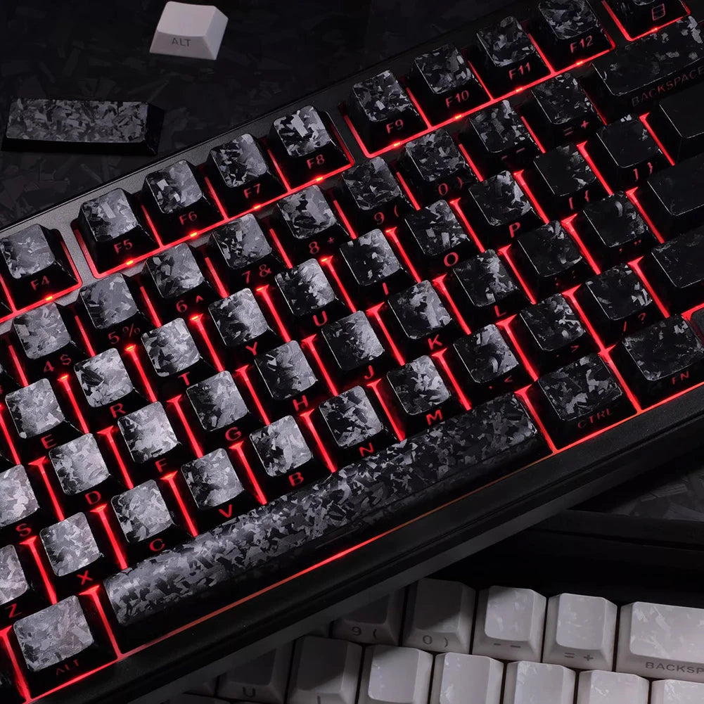Close-up of a black mechanical keyboard with carbon fiber keycaps and red backlit keys.