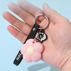 A hand holds a silver ring with a black leather strap and a pink flower charm for a floral design letter opener and paper cut
