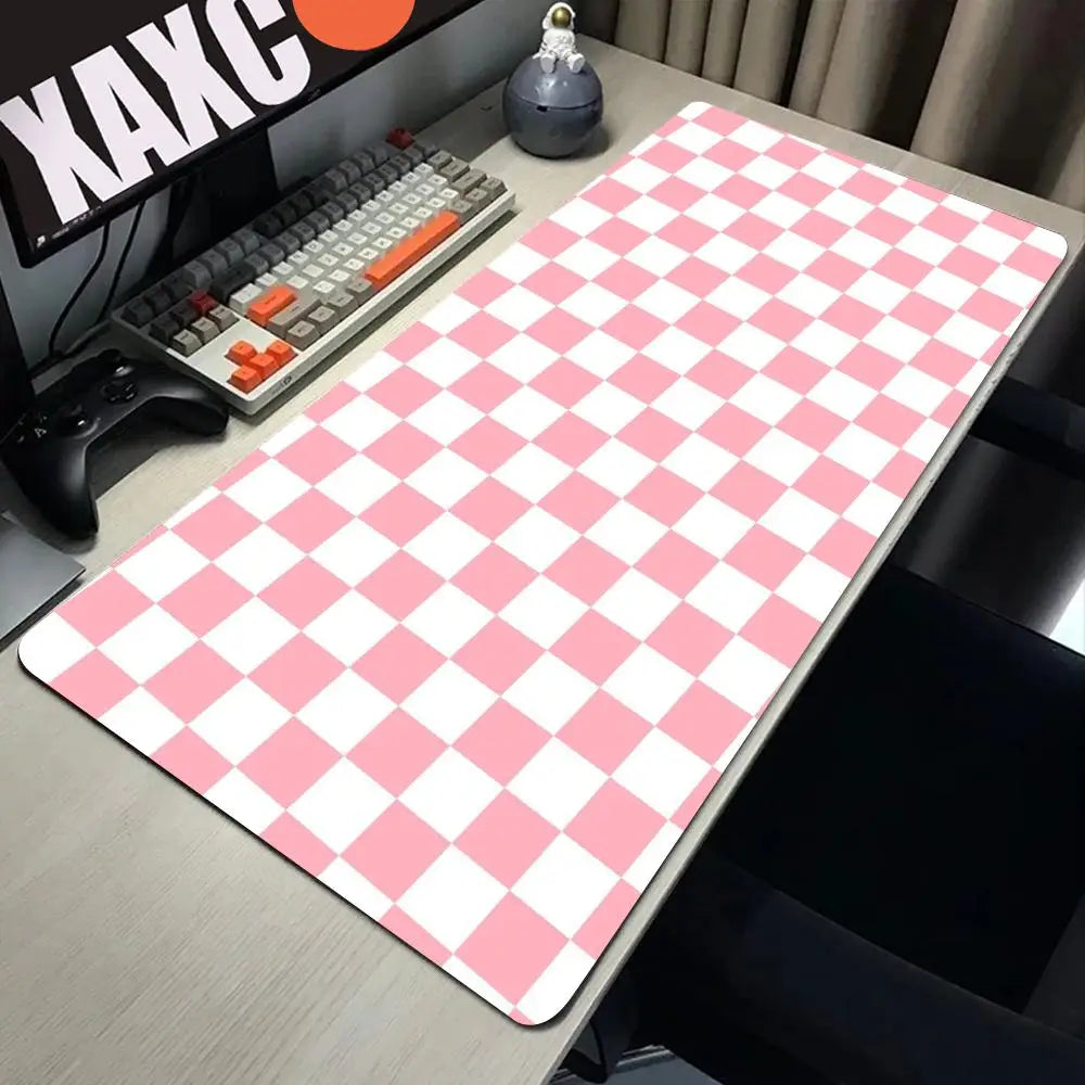 Pink and white checkered desk mat for gaming and work placed on a wooden desk.