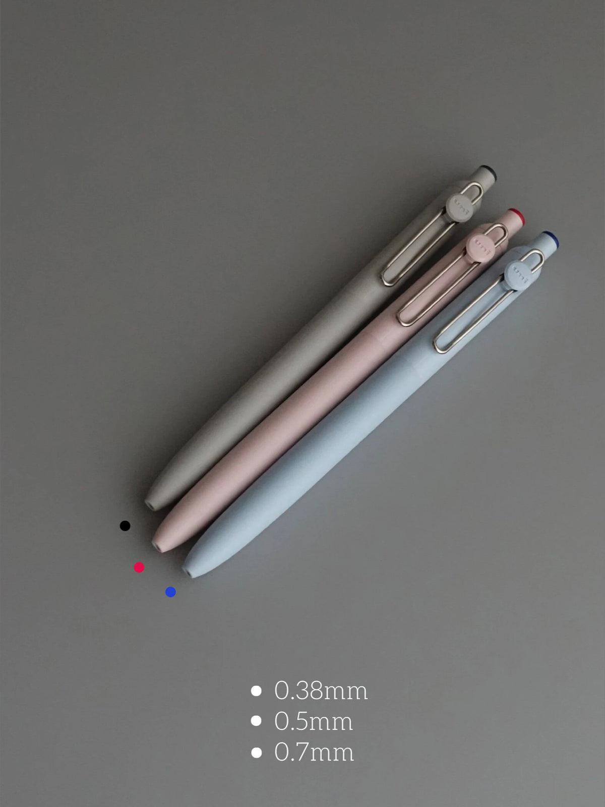 A collection of precision gel pens in various sizes and colors, including pink, gray, and blue, displayed diagonally on a neu