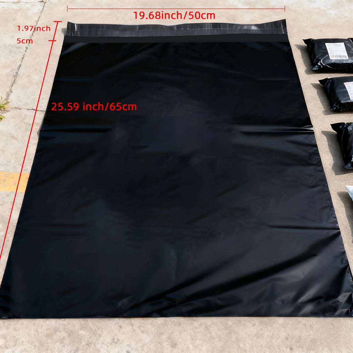 A black poly mailer bag is shown spread out on a concrete surface, with dimensions labeled.