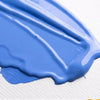 A swatch of bright blue gouache paint is spread across a white surface.