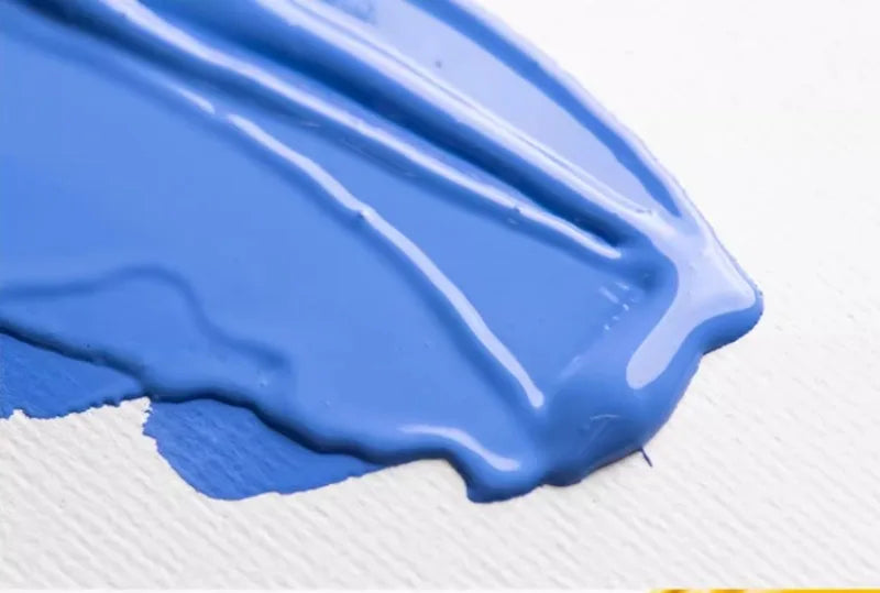 A swatch of bright blue gouache paint is spread across a white surface.