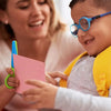 A young boy is using two-tone plastic scissors to cut paper with the help of an adult.
