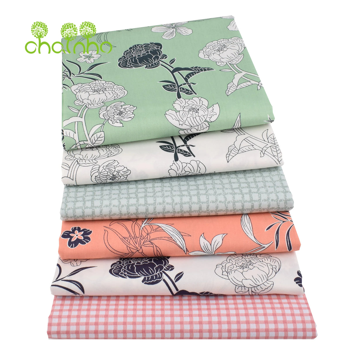Gestapelte Twill-Baumwollstoffe mit floralen und botanischen Mustern in verschiedenen Grüntönen, Rosa und Weiß.