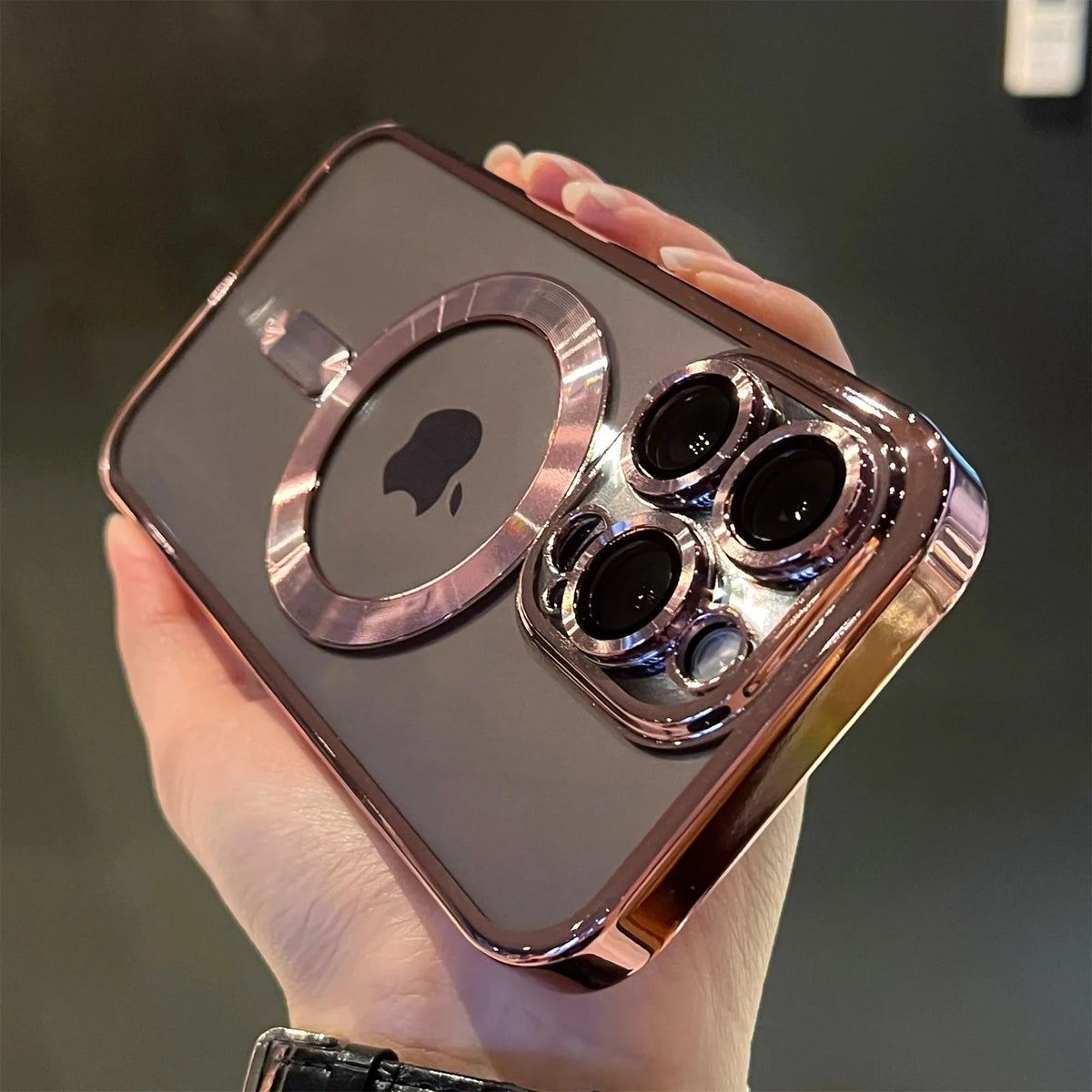 A hand holds a clear magnetic case with a rose gold plated finish for a MagSafe iPhone.