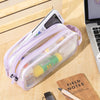 A purple transparent large-capacity pencil case is shown lying on a wooden surface next to a notebook and a pen.