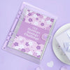 A clear plastic envelope planner with a purple floral pattern for a 100 Envelope Savings Challenge
