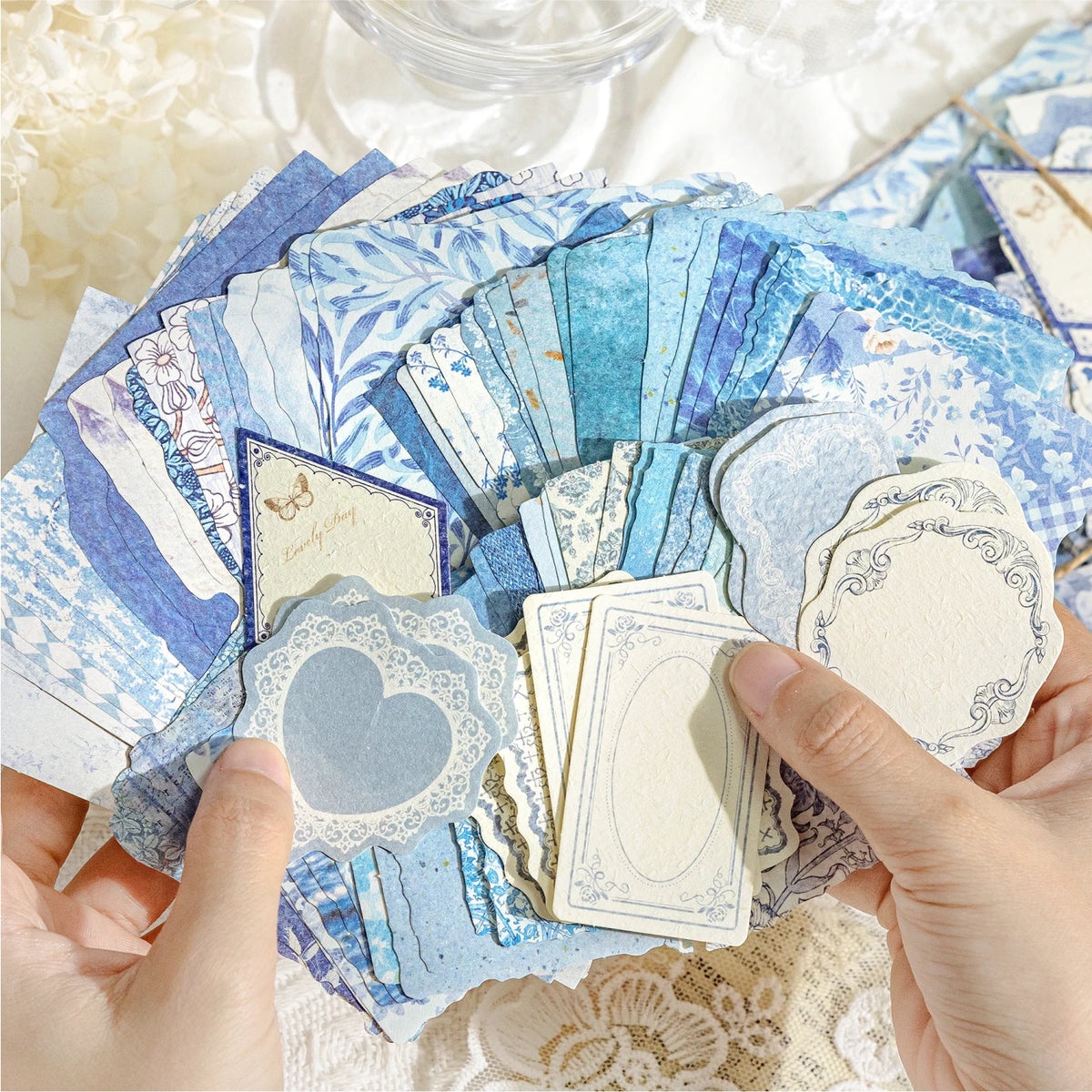 Hands holding a stack of vintage blue and white paper for crafting and scrapbooking