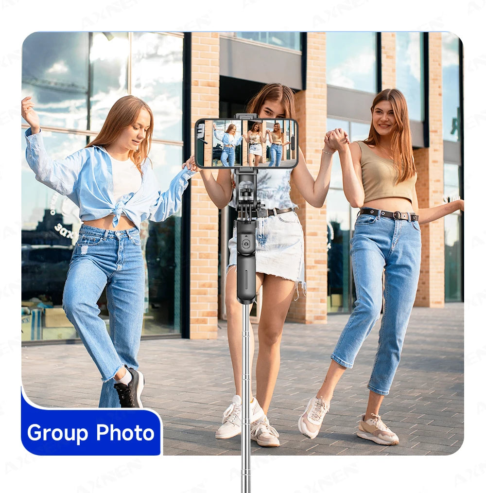 Three young women posing for a group photo using an extendable selfie stick tripod.