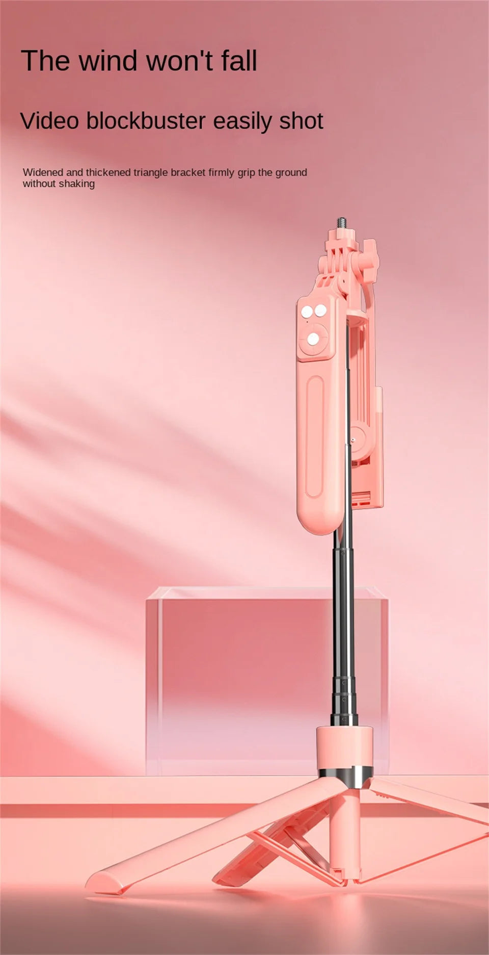 A pink 360 degree rotation selfie stick is shown resting on a glass box with soft lighting.