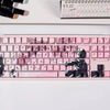 A close-up of a pink mechanical keyboard featuring Raven Sakura theme keycaps and a black silhouette design.
