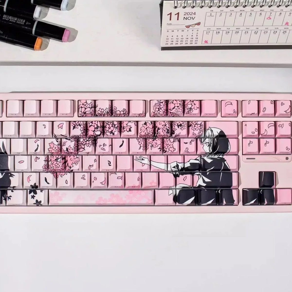 A close-up of a pink mechanical keyboard featuring Raven Sakura theme keycaps and a black silhouette design.
