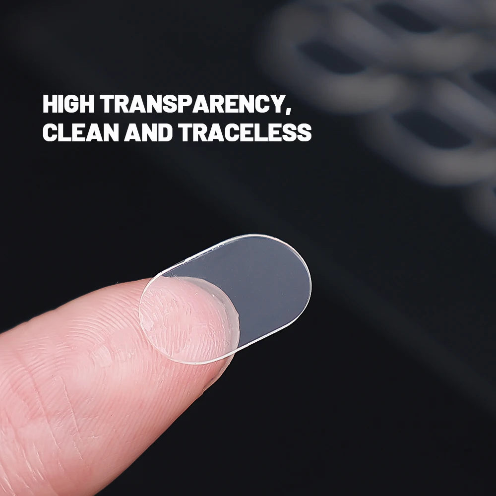 A hand holds a clear, double-sided adhesive fixer pad against a dark background.