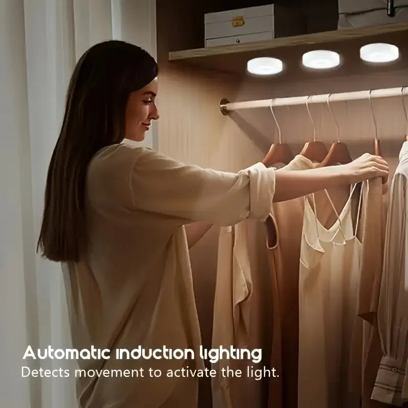 A woman is adjusting clothes on a wooden rack under automatic induction lighting in a closet.