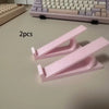Two pink ergonomic keyboard riser stands with anti-slip bases shown on a light surface.