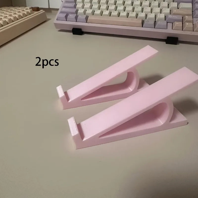 Two pink ergonomic keyboard riser stands with anti-slip bases shown on a light surface.