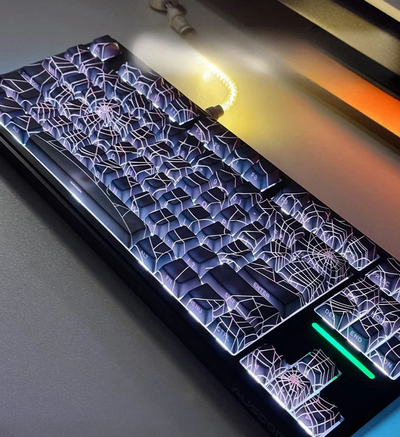 A close-up view of a translucent cherry mechanical keyboard featuring spiderweb-like keycap designs.