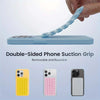 A hand is holding a light blue double-sided silicone suction cup grip designed to mount a phone.