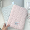 A pink quilted laptop sleeve with a light blue checkered lining is shown next to a silver Apple laptop.