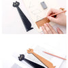 A hand uses a wooden drawing ruler shaped like a cat to measure lines on a sheet of paper.