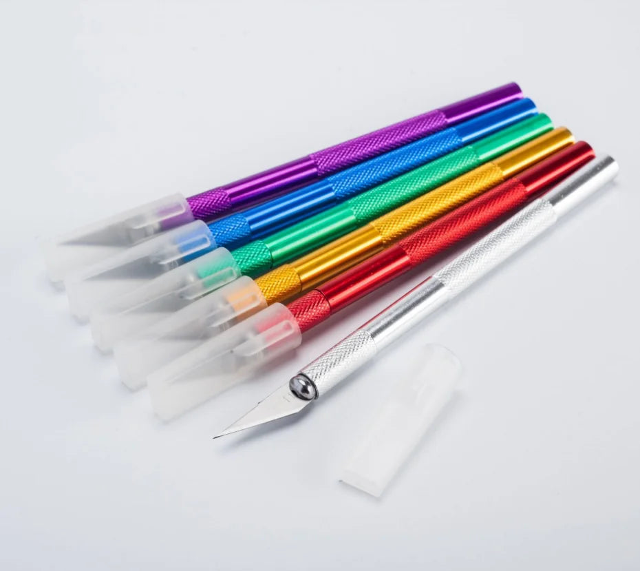 A collection of ten colorful precision craft knives with various blade shapes and colors laid out diagonally.