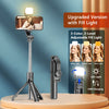 A black selfie stick tripod with an upgraded fill light is displayed on a wooden surface.