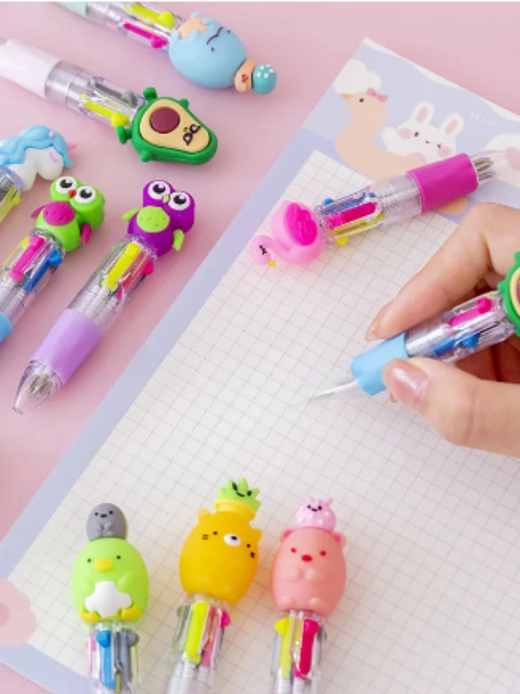 A collection of cute cartoon mini ballpoint pens in various colors and designs laid out on a white grid paper.