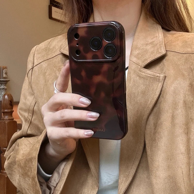 A hand holds an amber retro shockproof phone case for iPhone against a light brown jacket.