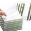 A hand is peeling a transparent sticky note from a stack of white memo pads.
