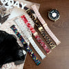A collection of resin beaded watch bands in various colors and patterns laid out on a wooden surface next to a wristwatch.