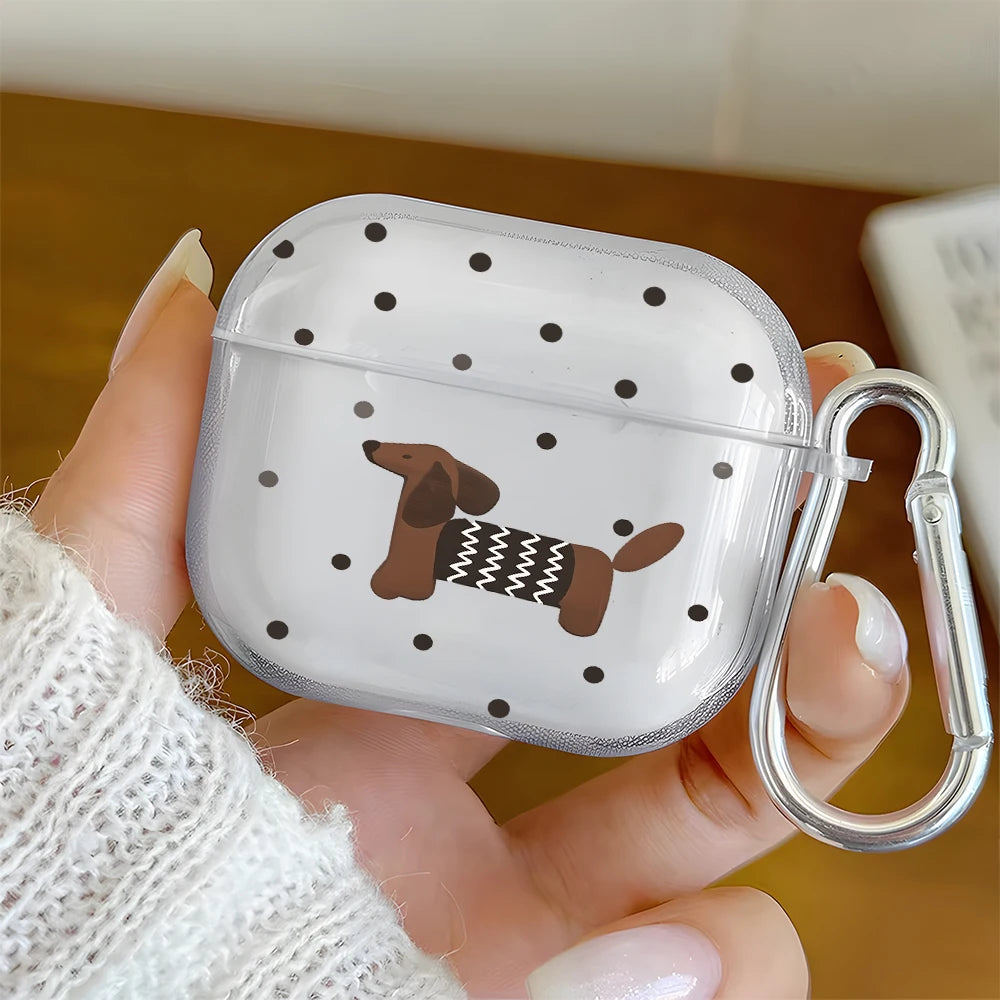 A hand holds a clear silicone case with a polka dot pattern featuring a dachshund design for AirPods.