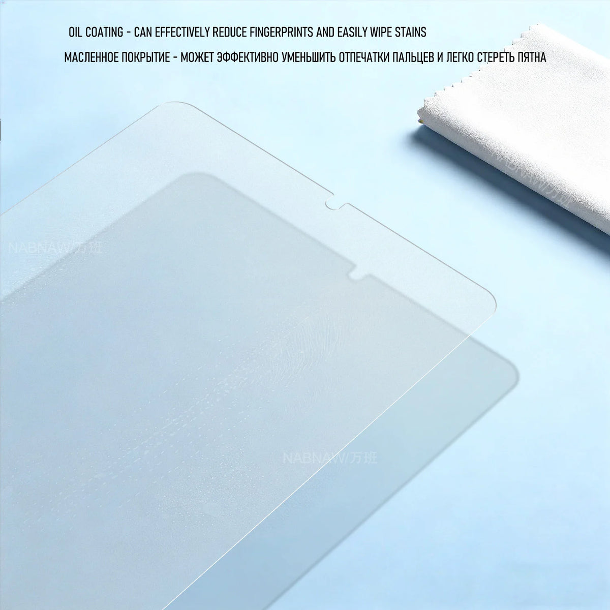 A clear tempered glass screen protector is shown on a light blue surface next to a white cloth.