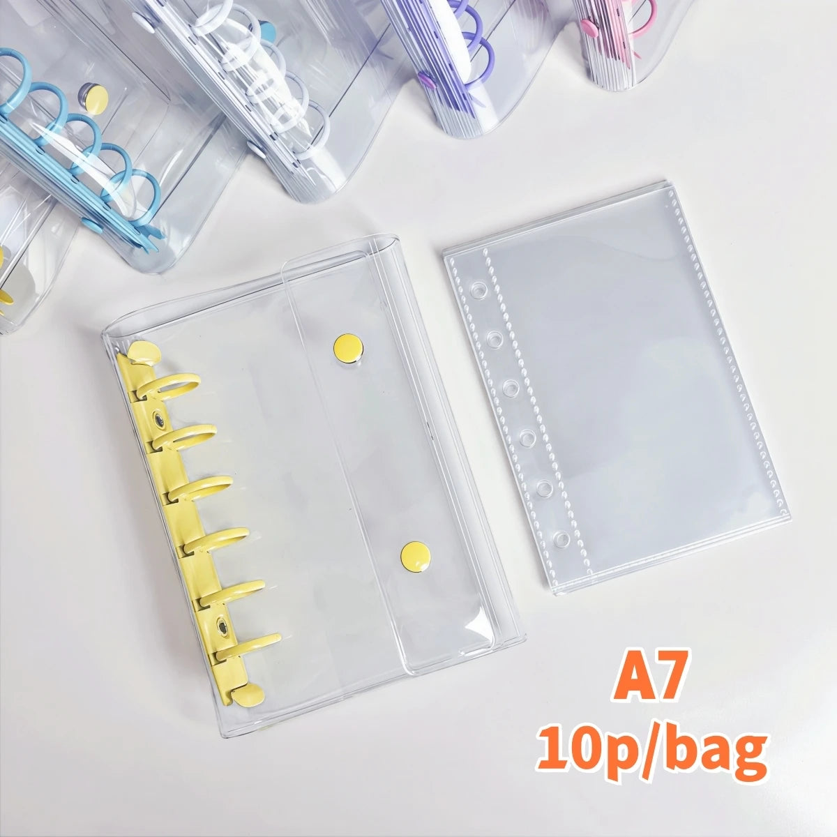 A clear double-button binder with yellow and purple accents is shown next to various colorful pens and a page labeled A7 10p/