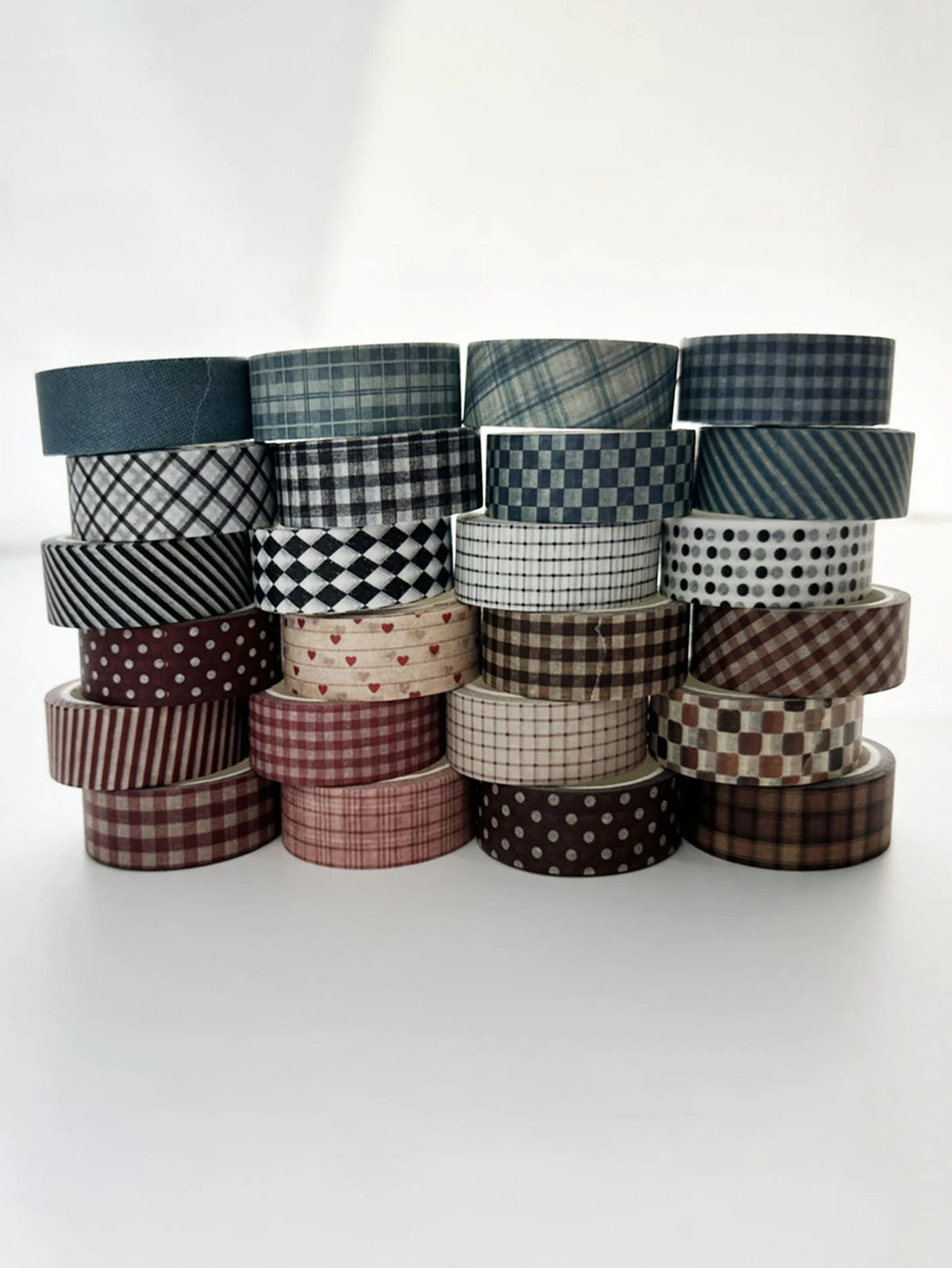 A collection of six rolls of plaid, grid, and polka dot washi tape in various muted tones stacked horizontally.