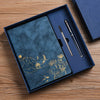 A dark blue luxury PU leather notebook set with a matching cover and pen displayed in a square box on a wooden surface.