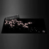 Black gaming mouse pad featuring a delicate pink cherry blossom branch design.