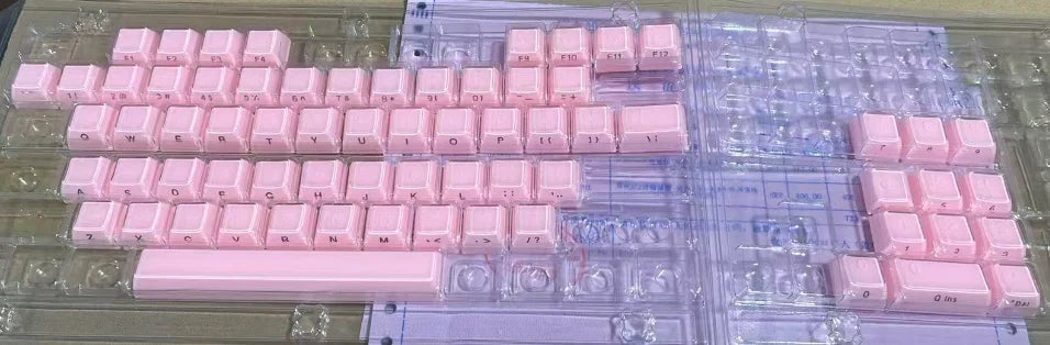 A set of translucent pink jelly keycaps for mechanical keyboards arranged on a clear plastic tray.