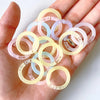 A hand holds several colorful reusable plastic binding rings in various translucent shades.