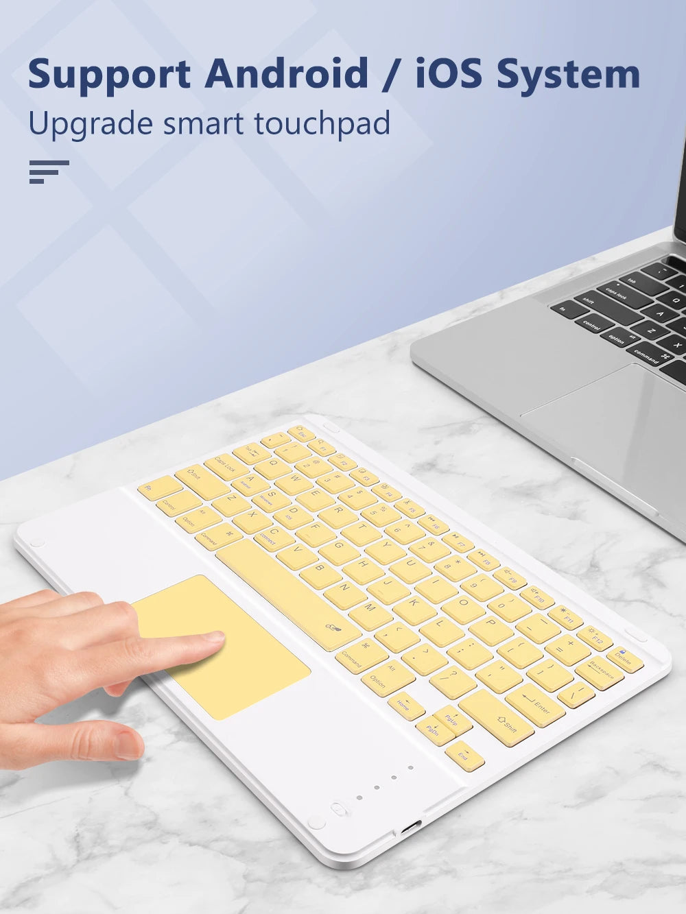 Une main interagit avec un clavier et une souris Bluetooth détachables jaunes pour un iPad sur une surface en marbre.