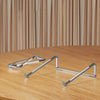 A silver foldable aluminum laptop stand with non-slip grips resting on a wooden table.