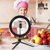 A smiling child is using an LED ring light with a tripod stand for photography or streaming.