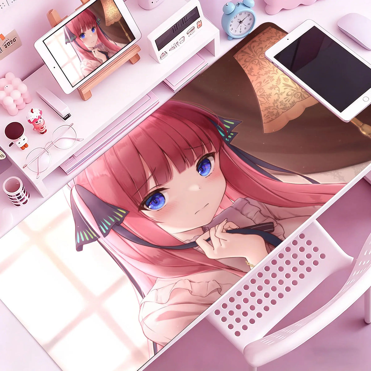 A close-up of a pink-haired anime girl resting her hand on a purple rubber mouse pad and desk mat surrounded by electronic de