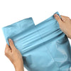 A hand is holding a light blue reusable waterproof poly shipping bag.