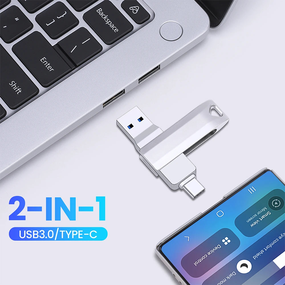 A silver USB 3.0 Type-C flash drive with a metal body is shown next to a laptop keyboard and a smartphone.