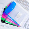 A collection of six colorful plastic expanding file pockets and a white ruler are displayed on a white surface.