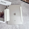 Un iPad plateado con una funda blanca protectora junto a un libro titulado Aurora.