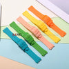 A collection of colorful silicone watch straps in orange, yellow, pink, and green laid out on a light background.