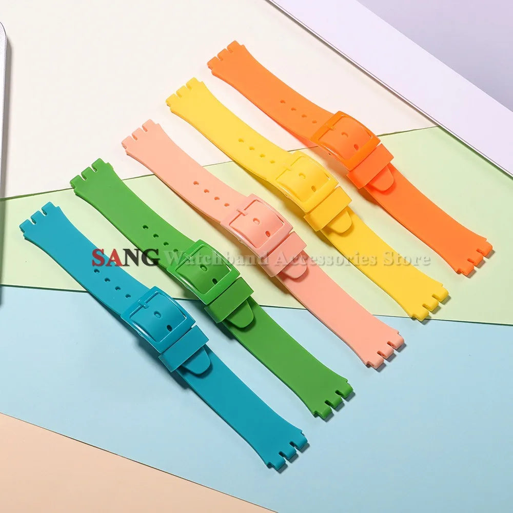 A collection of colorful silicone watch straps in orange, yellow, pink, and green laid out on a light background.