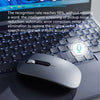 A gray AI voice typing mouse resting on a laptop keyboard with a speech processing algorithm graphic in the background.